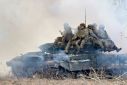 Ukrainian soldiers sit atop battle tanks deploying smokescreens as they join military drills