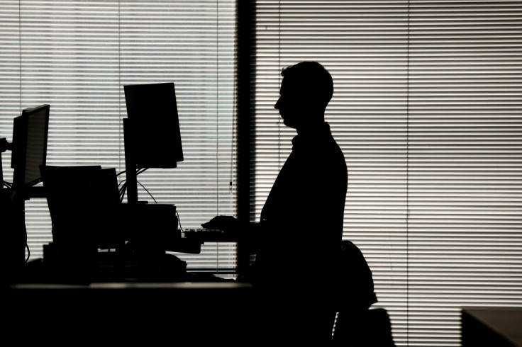 A man works at a computer on a standing desk