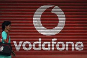 A woman walks past a large logo of Vodafone displayed on a shop in Mumbai May 20, 2010