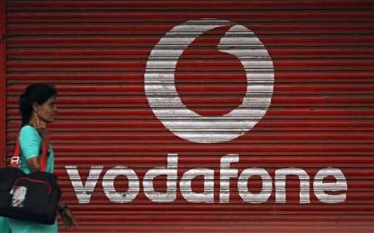 A woman walks past a large logo of Vodafone displayed on a shop in Mumbai May 20, 2010