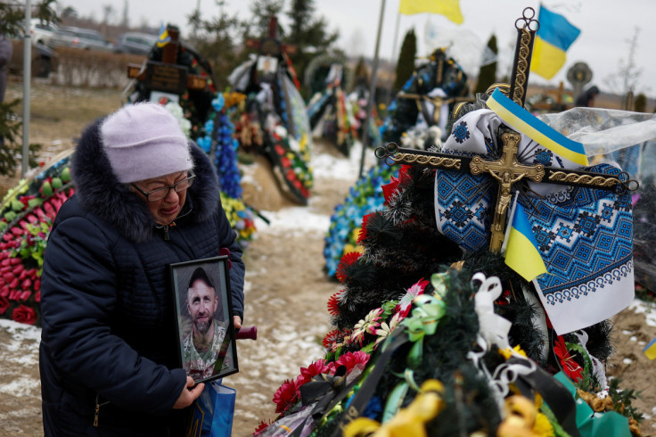 People visit graves of their relativises, on a day of the first anniversary of Russia's attack on Ukraine, in Bucha