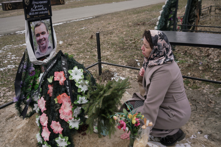 Alla Nechyporenko touches the grave of her husband Ruslan on a day of the first anniversary of Russia's attack on Ukraine, in Bucha