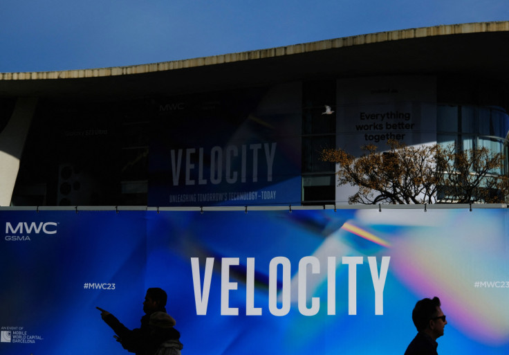 Workers walk past a billboard of GSMA's 2023 ahead of the Mobile World Congress (MWC) in Barcelona