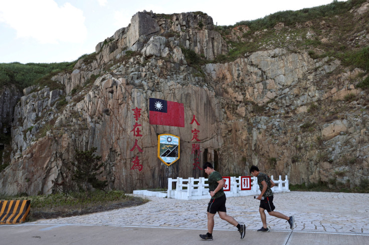 Soldiers march past a sign of the Taiwan flag on Dongyin island