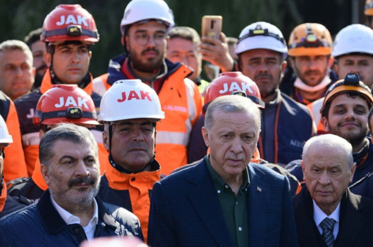 Turkish President Recep Tayyip Erdogan stands with rescue workers as he visits the hard-hit southeastern province of Hatay, the seen of destruction following two earthquakes on February 20, 2023.  A 7.8-magnitude earthquake hit near Gaziantep, Turkey, in 