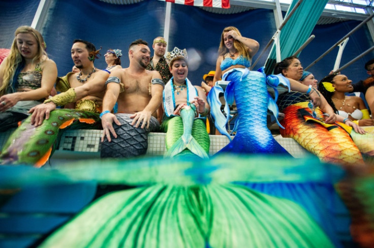 People dressed as mermaids and mermen sit poolside during the MerMagic Convention