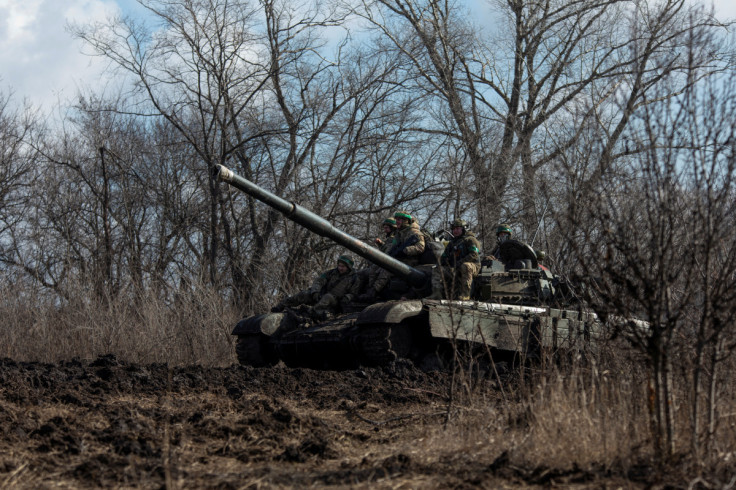 Ukrainian service members ride atop of a tank outside of the frontline town of Bakhmut