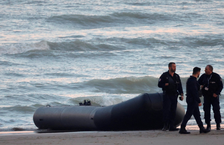 French policemen stand beside a dinghy lying on the beach after migrants tried to reach Britain