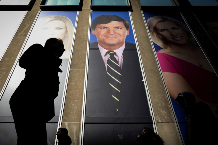 People pass by a promo of Fox News host Tucker Carlson on the News Corporation building in New York