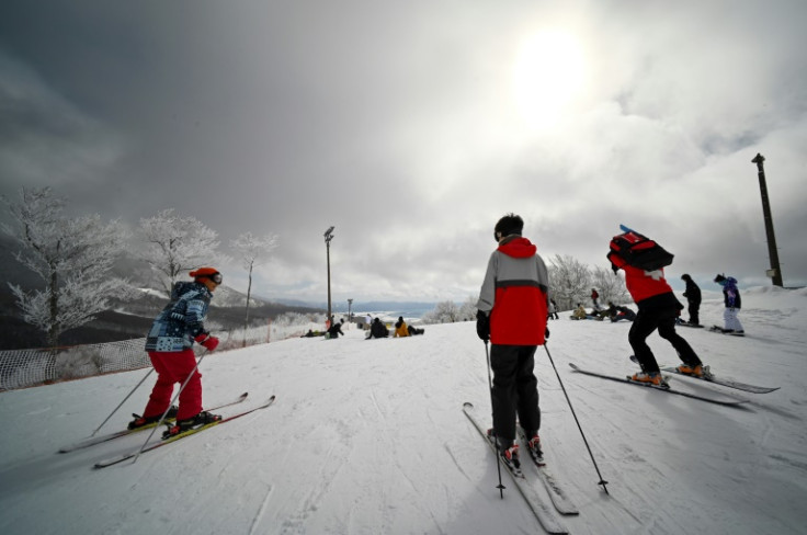 Skiers and snowboarders gathering at a ski course overlooking Lake Inawashiro