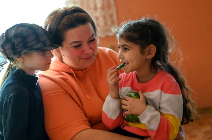 Veronika Komarnitskaya cradles a young Roma child on her knee in a refugee shelter in Uzhhorod, Ukraine