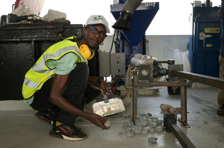 A Senegalese entrepreneur picks up balls made from recycled plastic at a demonstration on the ship