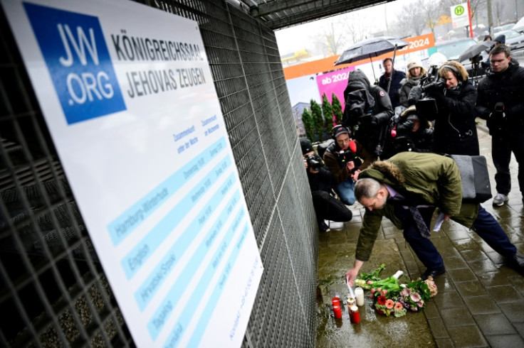 A clutch of people placed flowers in front of a sign displaying the centre's opening hours
