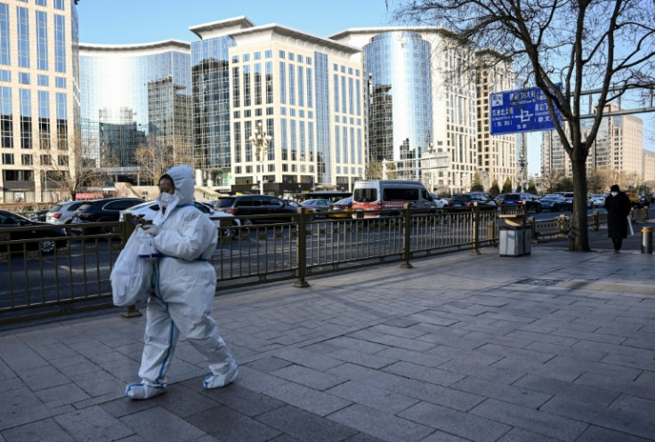 A woman wearing personal protective equipment walks along a street in Beijing in December 2022