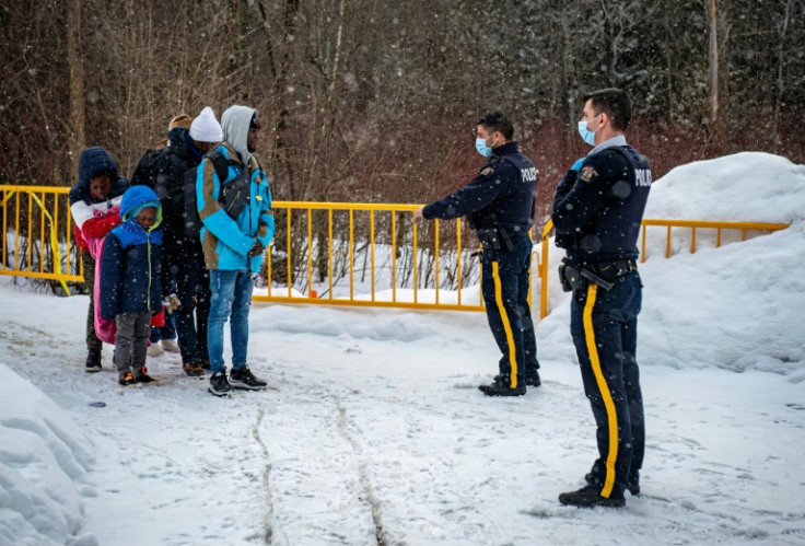 Officers speak to migrants as they arrive at the Roxham Road border crossing in Canada on March 2, 2023