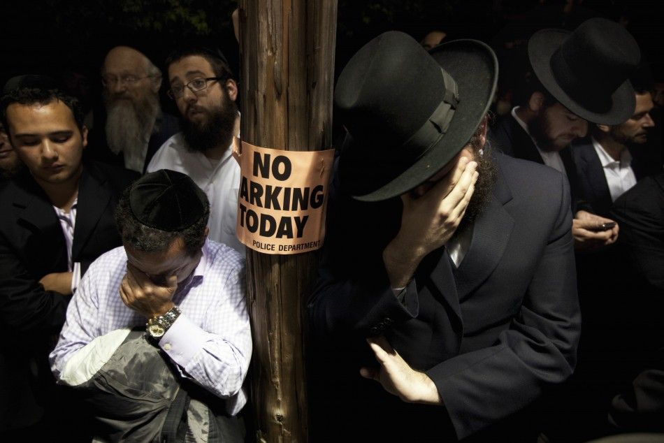 Men weep while listening to the funeral of Leibby Kletzky outside a synagogue in the Brooklyn borough of New York