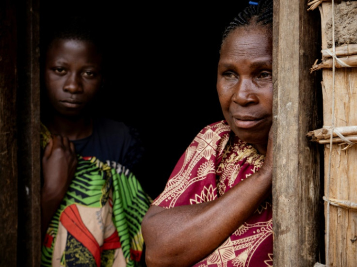 A woman and her daughter look on in front of their home the day after the attack on two villages which killed more than 40