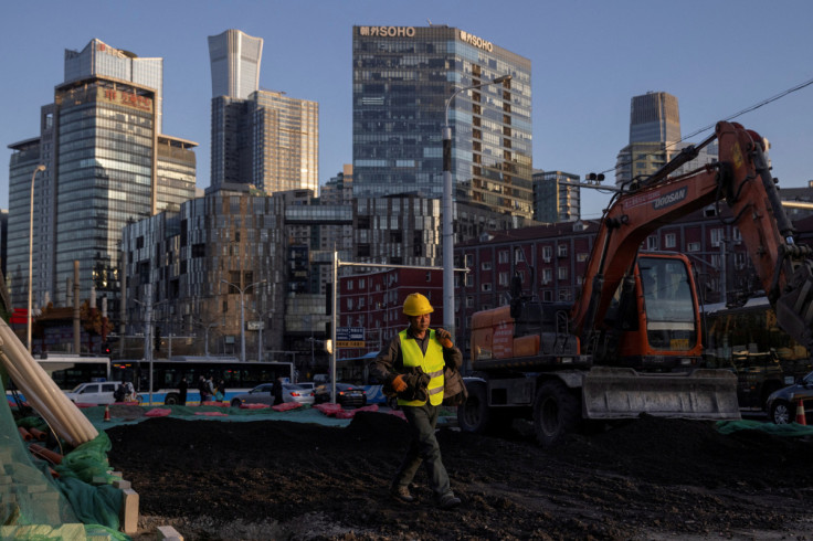 A worker walks across a construction site in the Central Business District, ahead of the opening of the National People's Congress (NPC) in Beijing