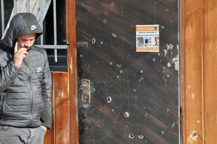 A Palestinian man speaks on his mobile phone outside a bullet-riddled door after the Israeli army said it killed five 'terrorists' near Jericho on February 6, 2023