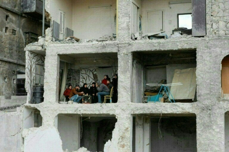 A family huddle in the ruins of their home destroyed by the 7.8-magnitude quake in Aleppo