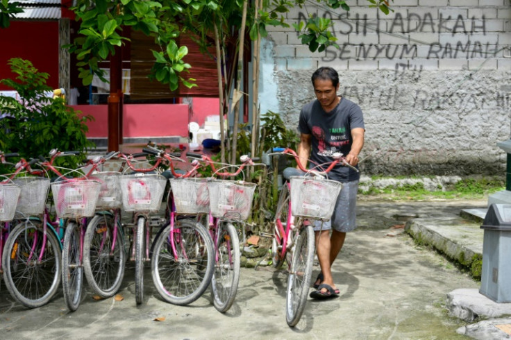 Edi Mulyono stands next to a sign that reads: "Is there still a friendly smile for the people?", written as a protest against environmental issues faced by Pari islanders