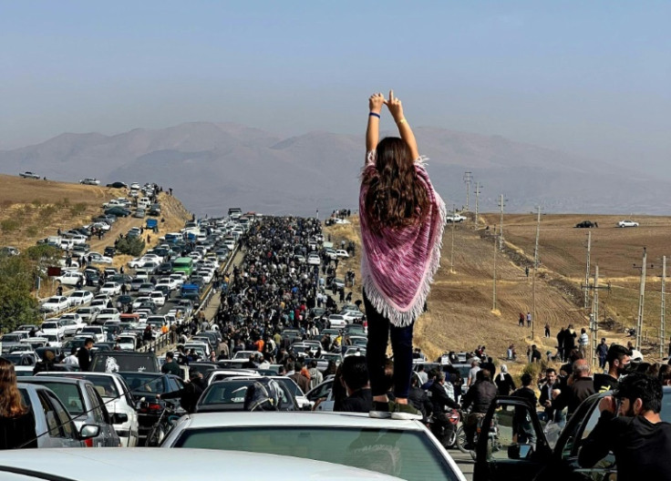A Iranian woman shunning the mandatory headscarf joins thousands of protesters in a procession in Amini's hometown Saqez commemorating her death in custody in Tehran