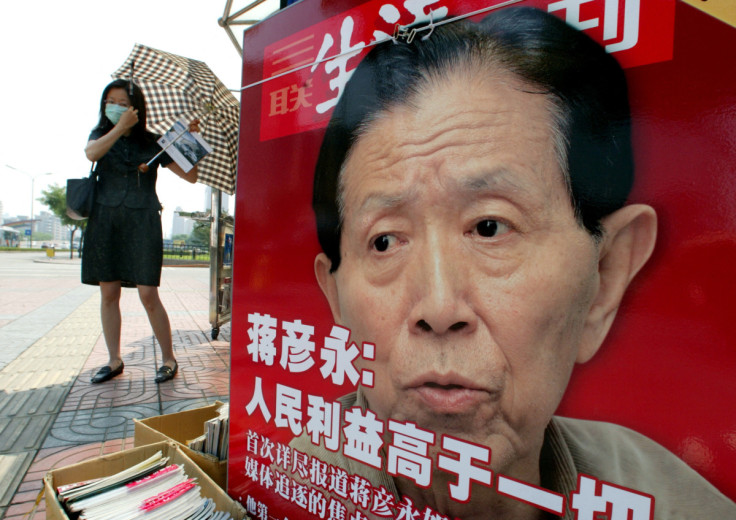  A CHINESE WOMAN ADJUSTS HER FACE MASK AT A NEWSPAPER STALL FEATURING APHOTO OF DR JIANG YANYONG IN ...