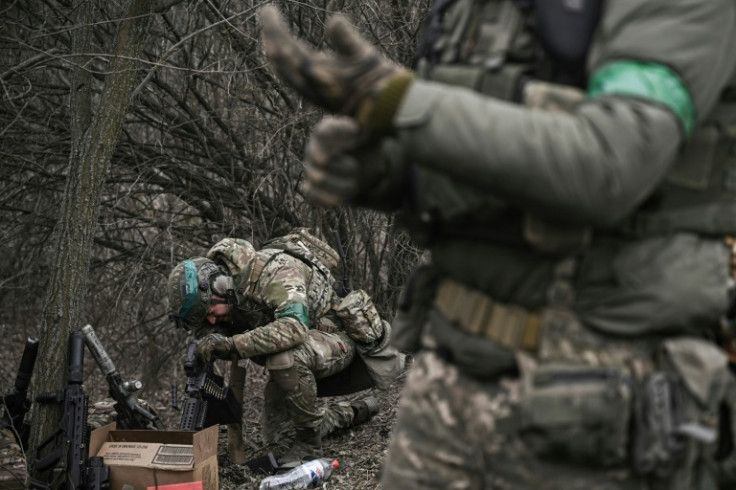 A Ukrainian special unit member prepares his weapon in woods near Bakhmut