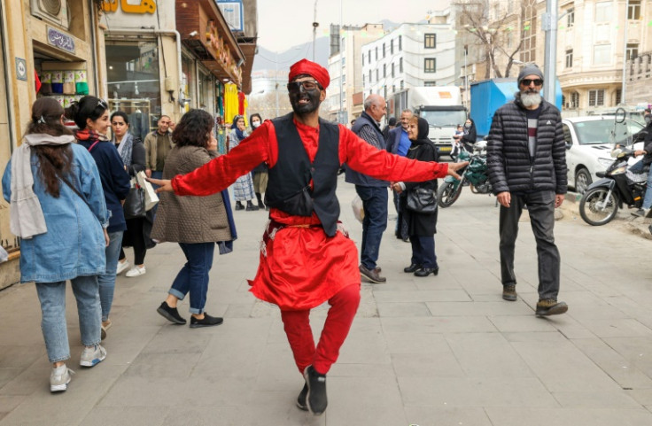 An Iranian man dressed as the fictional folklore character Hajji Firuz performs on at a street in Tehran ahead of the Nowruz New Year festival