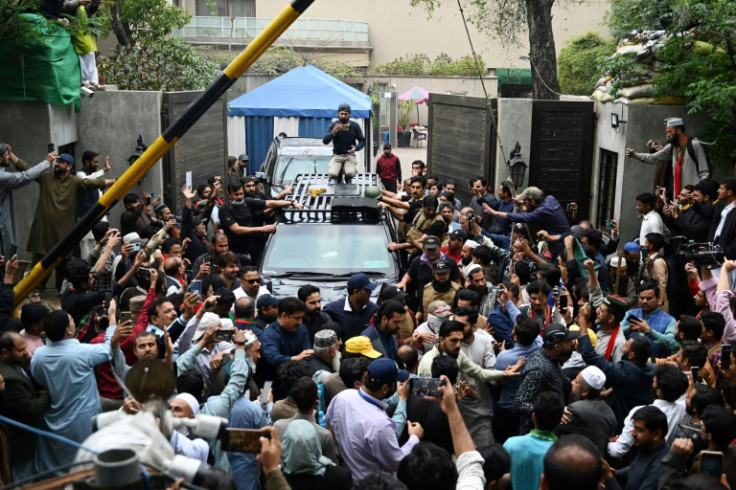 Supporters of Pakistan's former prime minister Imran Khan gather around his car as he leaves his Lahore residence to appear in court in Islamabad