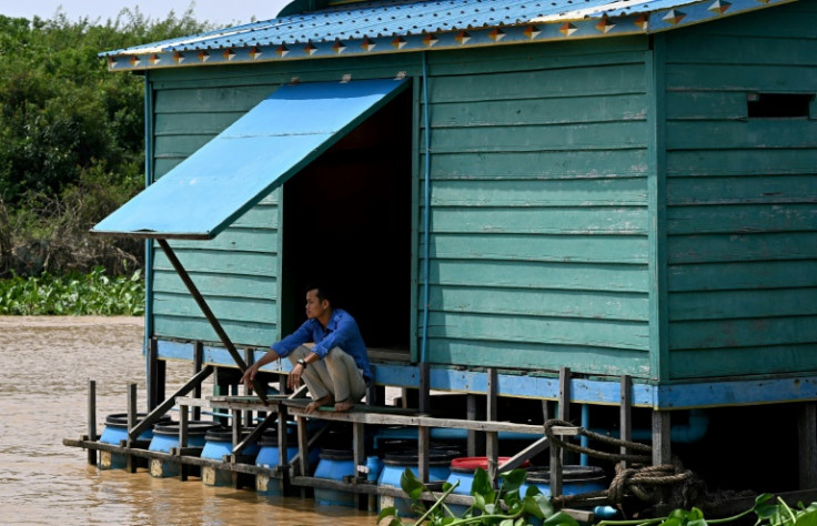 A teacher squats above floating toilets in Chong Prolay village on Cambodia's Tonle Sap lake