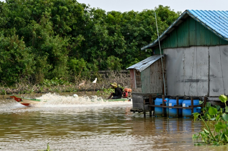 A villager drives a boat near floating toilets in Chong Prolay village