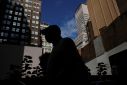 A man is seen silhouetted wearing a protective face mask, amid the coronavirus disease (COVID-19) pandemic, walking near the financial district of New York City