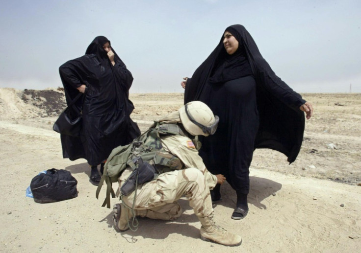 A female US soldier frisks Iraqi women at a checkpoint in the southern Iraqi town of Um Qasr, in this file photo from April 5, 2003