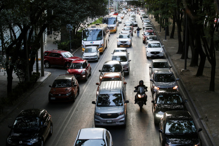 A man rides his motorcycle past cars queue in traffic during rush hour in Mexico City