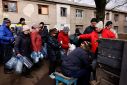 Residents queue to receive food and water brought in by Ukraine's State Emergency Service members, in Chasiv Yar