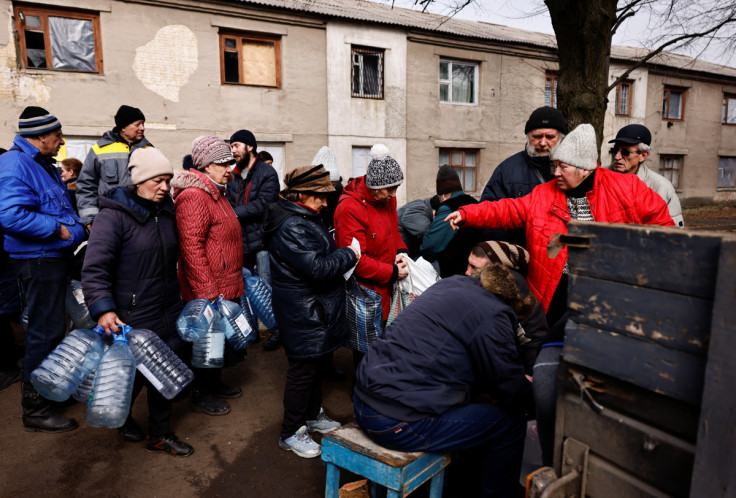 Residents queue to receive food and water brought in by Ukraine's State Emergency Service members, in Chasiv Yar