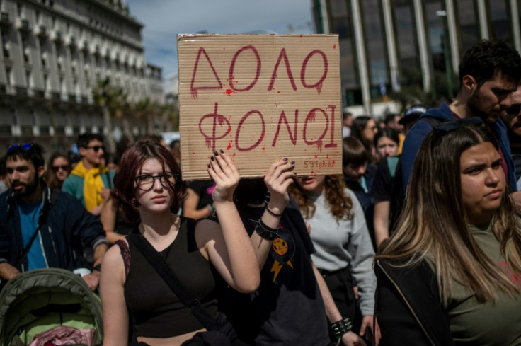 Protestors hold a placard that reads "murderers" as thousands march through the streets of Athens over the country's worst rail tragedy
