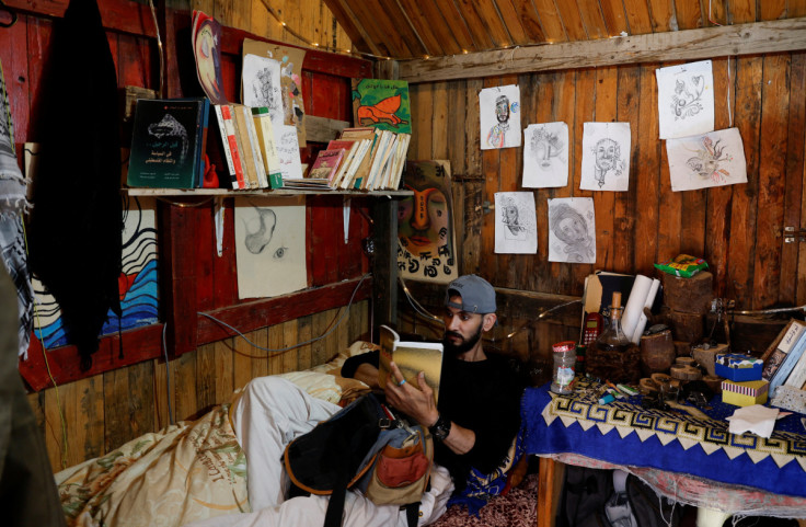 Moamen Toman, a Palestinian man, reads a book in his coffee shop in Gaza Strip