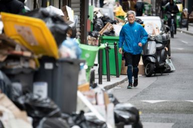 A jogger runs past garbage bags that have been piling up on the pavement as waste collectors are on strike since March 6 to protest against the French government's proposed pensions reform
