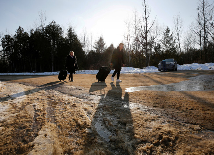 People walk with their luggage on Roxham Road before crossing the US-Canada in Champlain