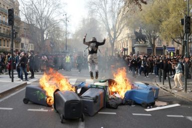 A protester jumps next to a fire of waste containers during a demonstration in Toulouse, southwestern France