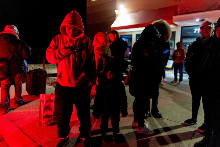 People wait for transport to cross into Canada at Roxham Road, in Plattsburgh