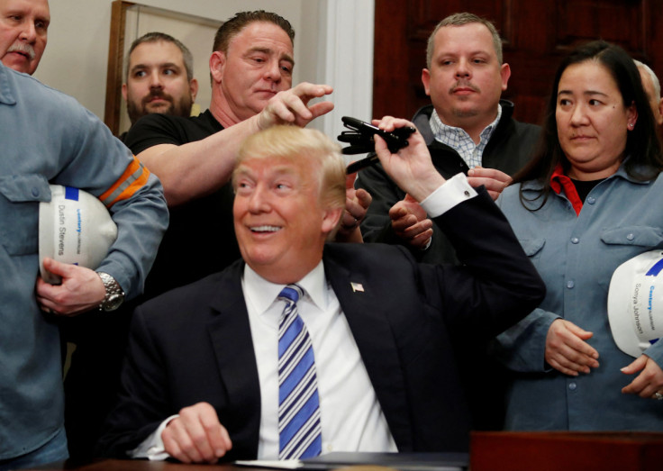 U.S. President Donald Trump signs a presidential proclamation placing tariffs on steel and aluminum imports while surrounded by workers from the steel and aluminum industries at the White House in Washington
