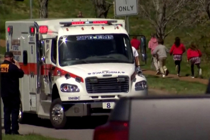 Children run past an ambulance near the Covenant School after a shooting in Nashville