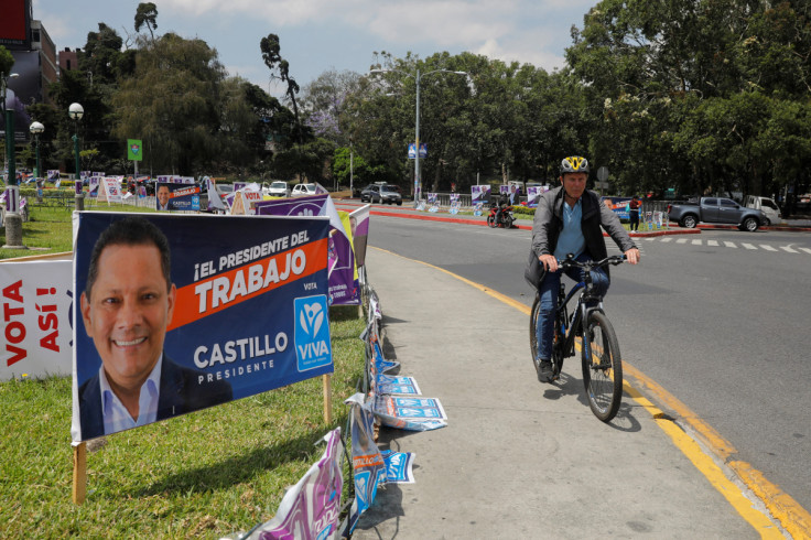 A person rides a bicycle next to posters of candidates for the general elections, in Guatemala City