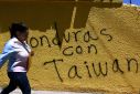 A woman in Tegucigalpa walks past a wall with graffiti that reads 'Honduras with Taiwan'