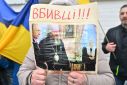 A woman holds picture depicting Metropolitan Pavlo staing next Russian President Vladimir Putin and reading "Killers!!!" as they rally in Kyiv