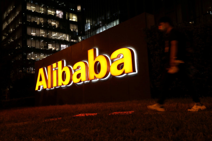 Man walks past a logo of Alibaba Group at its office building in Beijing