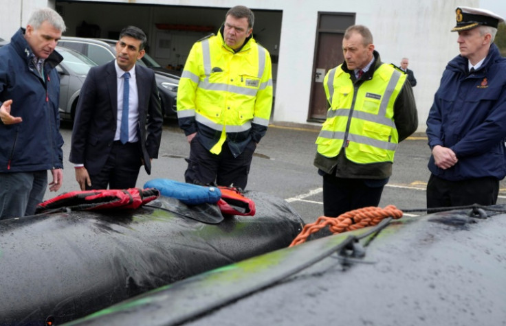 Britain's Prime Minister Rishi Sunak looks at buoyancy aids and an inflatable rubber dinghy during a visit to the port of Dover